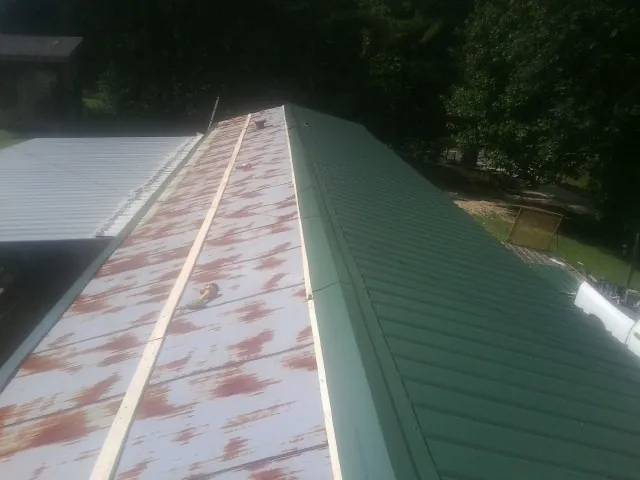 Old rusted panels beside newly installed green metal roofing — Wind Damage Roof Repair by Roofing Brothers in Jamul