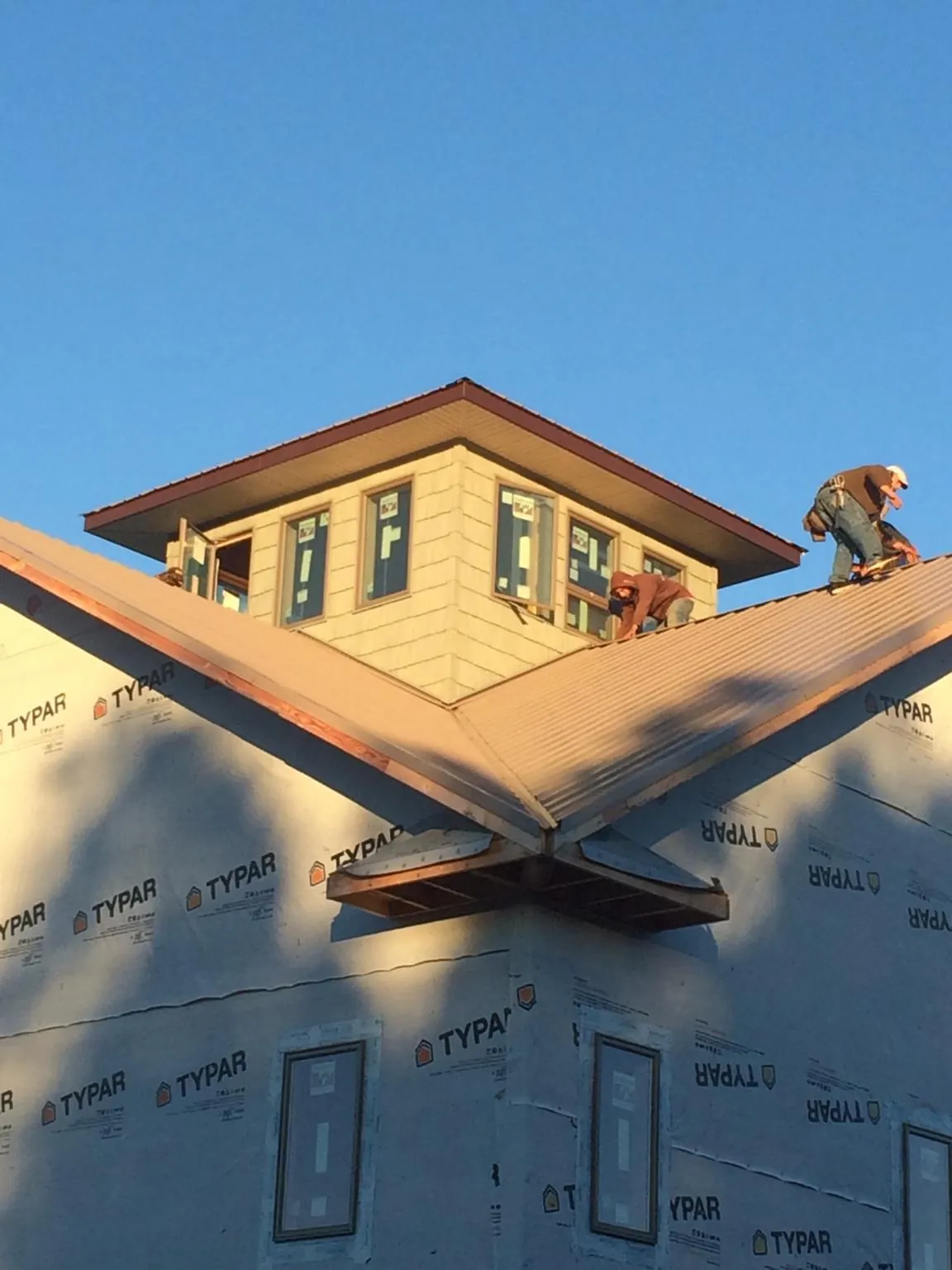 Roofers working around a rooftop cupola on a new metal roof at sunset — Roof Waterproofing in Jamul by Roofing Brothers